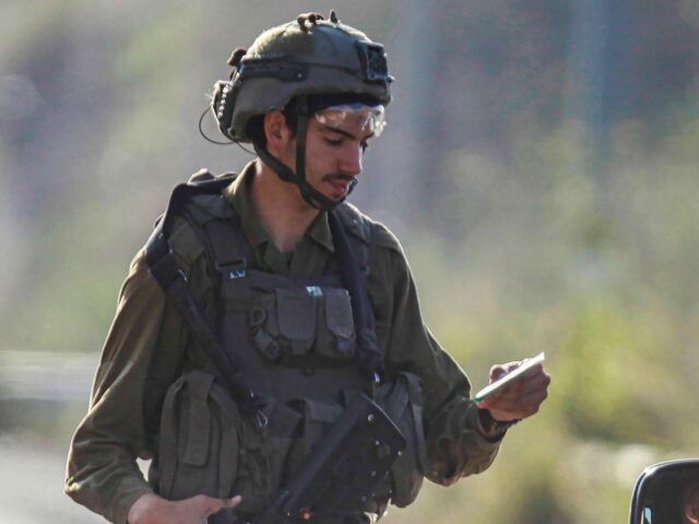 NABLUS, WEST BANK, PALESTINE - 2023/07/06: An Israeli soldier checks the phones of Palesti