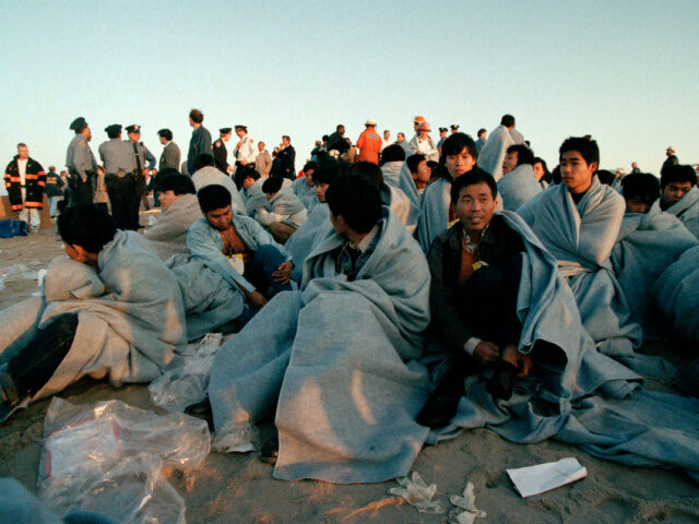 Illegal Chinese immigrants huddle wrapped in bankets in the morning chill on the beach in