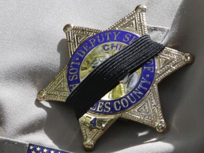 A black band partially covers the badge of the Los Angeles County Deputy Sheriff who atten