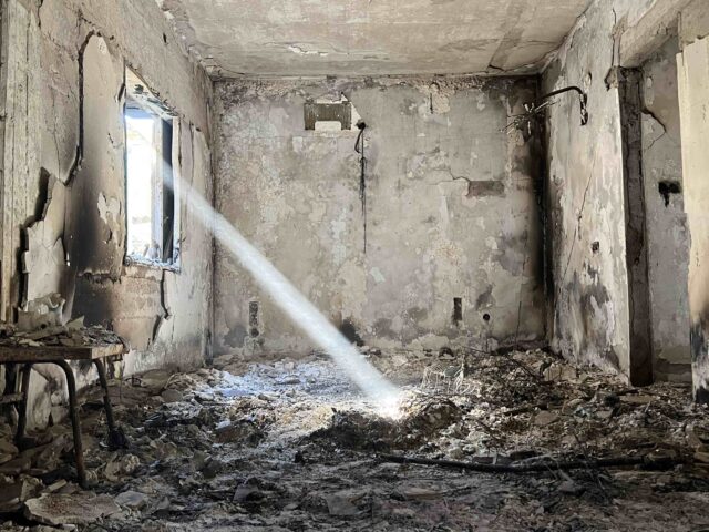 A ray of light shines into the burnt ruin of a house destroyed by Hamas terrorists in the