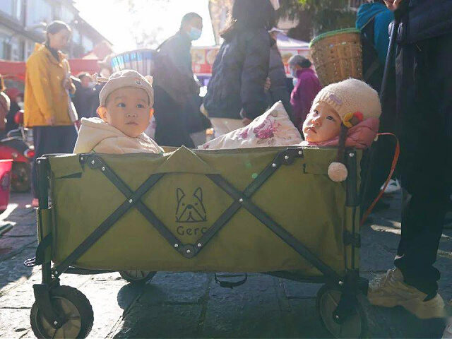 DALI, CHINA - JANUARY 14: Children sit in a stroller at a country fair ahead of the Chines