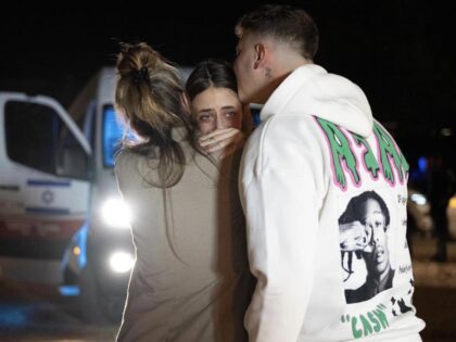 Mia Shem (or, alternatively, Maya Schem) being embraced by her family upon her release from Hamas custody, Hatzerim Air Base, Israel, November 30, 2023. Her right arm was wounded in the Oct. 7 attack and appears immobile. (Courtesy Government Press Office)