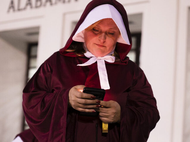 Woman wearing Handmaid costume protests in front of the Alabama State House after the Stat