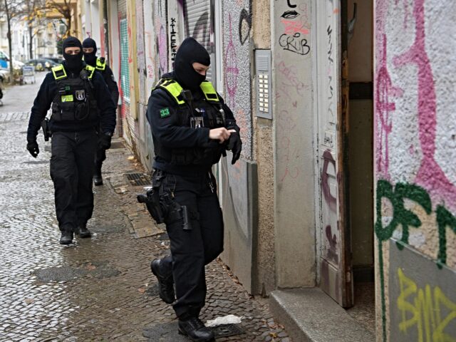 23 November 2023, Berlin: Police officers walk to the entrance of a building during a raid