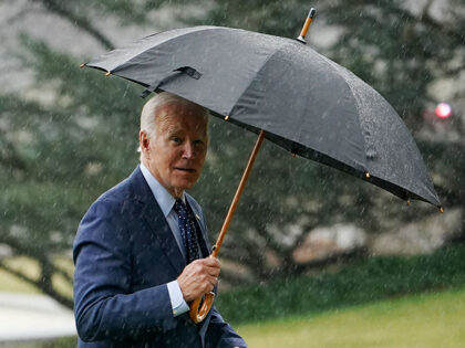 US President Joe Biden holds an umbrella as he walks across the South Lawn upon return to