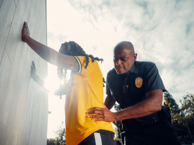 A police officer frisks a man (Pexels/Kindel Media).
