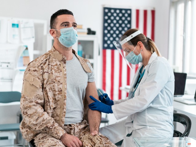 Doctor wearing protective work wear injecting COVID-19 vaccine to solider (Stock photo via Getty)