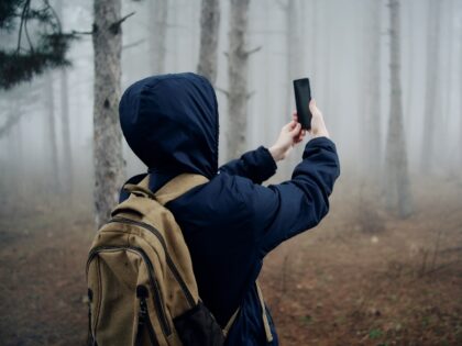 teen with smartphone in forest