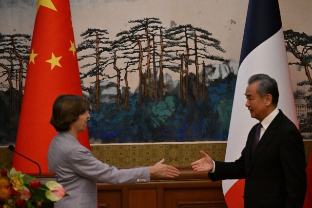 China's Foreign Minister Wang Yi (R) shakes hands with French Foreign Minister Catherine C