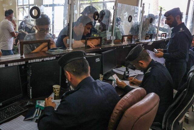 Civilians leaving Gaza display their documents as dual national Palestinians and foreigners prepare to cross the Rafah border with Egypt