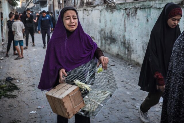 A girl carrying a bird cage flees following an Israeli strike in Rafah in the southern Gaz