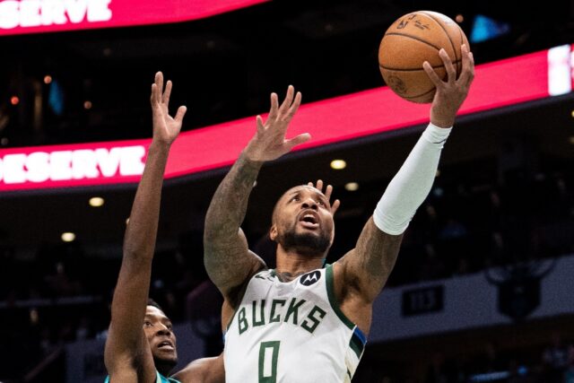 Milwaukee's Damian Lillard drives to the basket while guarded by Brandon Miller of the Cha