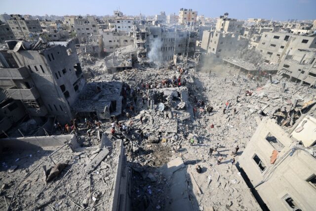 Palestinians stand in the rubble of buildings destroyed in an Israeli strike on the Bureij refugee camp in the central Gaza Strip on November 2, 2023, as battles between Israel and the Palestinian Hamas movement rage