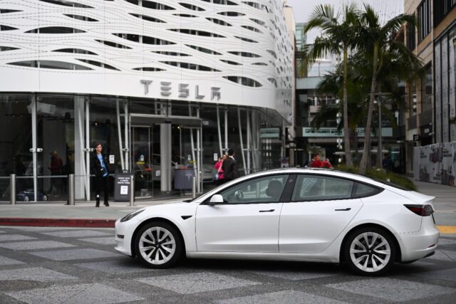 A Tesla electric vehicle drives past the Tesla Inc Santa Monica Place store, in Santa Moni
