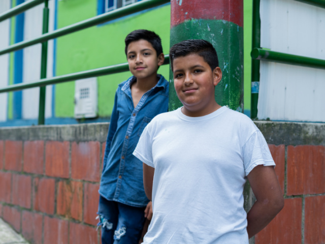 Latin brothers with an average age of 9 to 11 years dressed comfortably are on the street of the neighborhood where they live looking towards the camera that portrays them showing a beautiful smile.