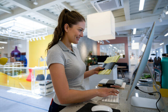 Happy woman working as a cashier at a furniture store and registering items