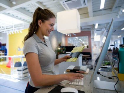 Happy woman working as a cashier at a furniture store and registering items
