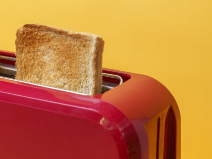 High angle view of red toaster toasting two bread slices on yellow background