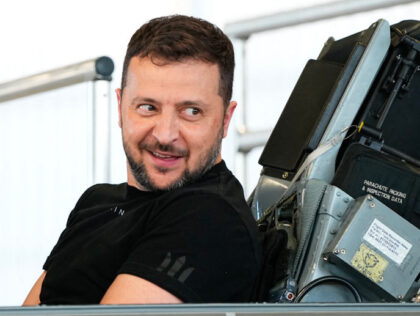 Ukrainian President Volodymyr Zelensky reacts as he sits in a F-16 fighter jet in the hang