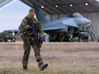 05 December 2023, Romania, Constanta: A Bundeswehr soldier walks past a German Eurofighter