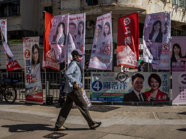 A man walks past signs for candidates during the district council election in Hong Kong on