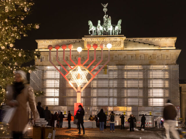 Tourists visit the Hanukkah candelabrum installation during the Jewish Hanukkah festival, in front of the Brandenburg Gate in Berlin, Germany, on Thursday, Dec. 7, 2023. Chancellor Olaf Scholz and top officials in his governing coalition will reconvene on Monday afternoon to try to seal an agreement on a revised 2024 budget, according …