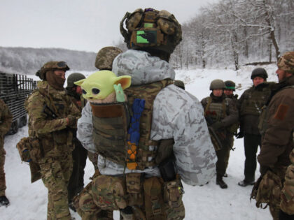 In Kharkiv Region, Ukraine, on December 14, 2023, a serviceman is carrying a Baby Yoda toy