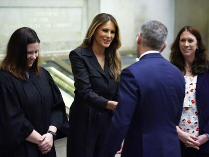 Former U.S. first lady Melania Trump (C) shakes hands with new U.S. citizens during a natu