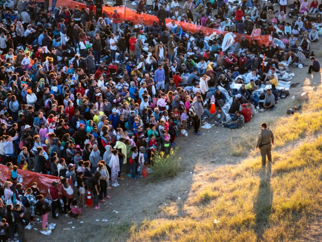 EAGLE PASS, TEXAS - DECEMBER 17: In an aerial view, a U.S. Border Patrol agent watches over migrants waiting to be processed after crossing from Mexico into the United States on December 17, 2023 in Eagle Pass, Texas. A surge of migrants, as many as 12,000 per day, crossing the U.S. southern border has overwhelmed U.S. immigration authorities. (Photo by John Moore/Getty Images)