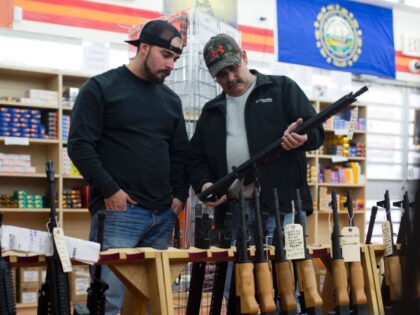 Customers look at a long gun at a gun shop on November 5, 2016, in Merrimack, New Hampshir