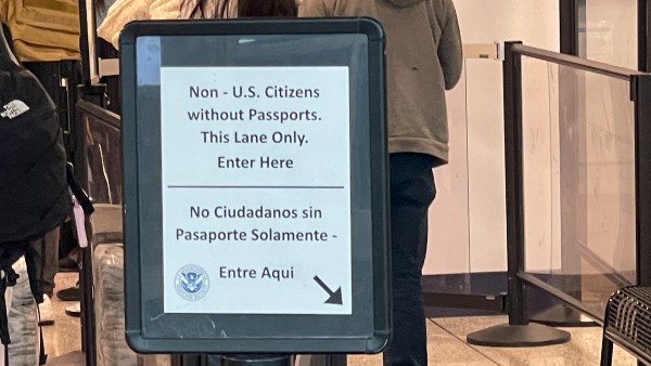 An NGO staffer escorts migrants through the Tucson International Airport to a special TSA screening line. (Randy Clark/Breitbart Texas)