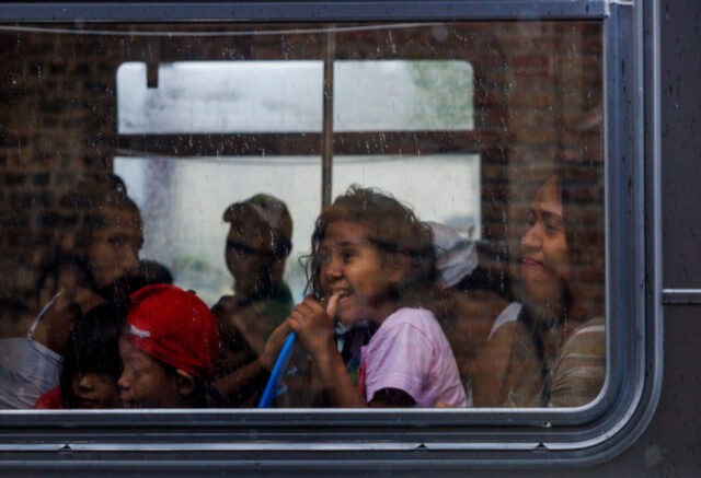 Migrants look out the window as they ride a CTA bus leaving the High Ridge YMCA shelter to