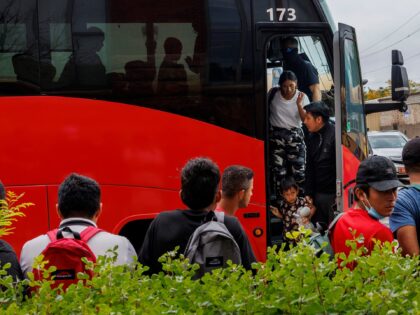 A group of migrants exits a bus near a Greyhound station after being transported from Texa