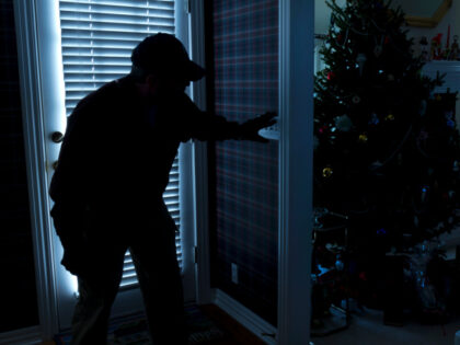 This photo illustrates a burglary or thief breaking into a home at night through a back do