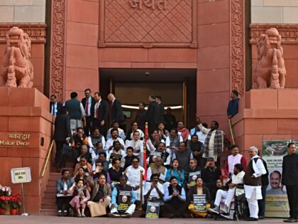 Indian lawmakers sit on the stairs of the parliament building in protest against the suspe