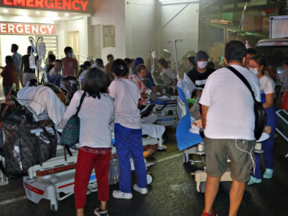 Residents and medical personnel evacuate patients from inside a hospital after a 7.6 earth
