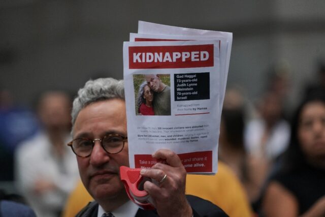A man holds a picture of hostages Gad and Judith Weinstein Haggai -- both of whom have bee