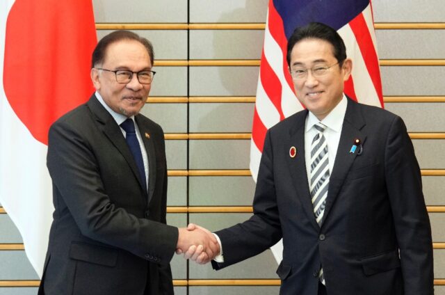 Japan's Prime Minister Fumio Kishida (R) shakes hands with Malaysia's Prime Minister Anwar