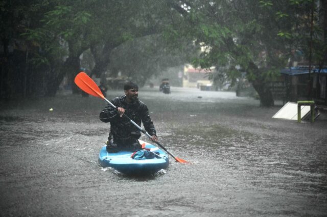 A man uses a kayak to cross a flooded street after heavy rains in Chennai