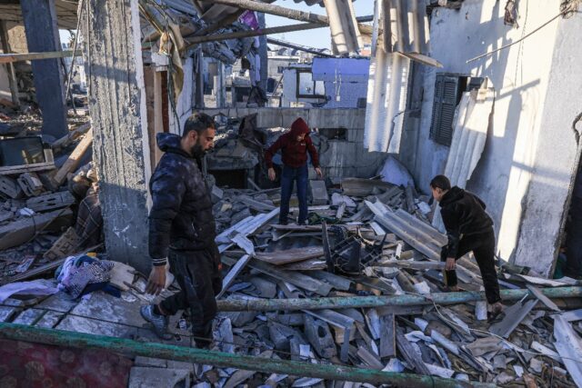 Palestinians search through the rubble of a building following an Israeli strike in the so