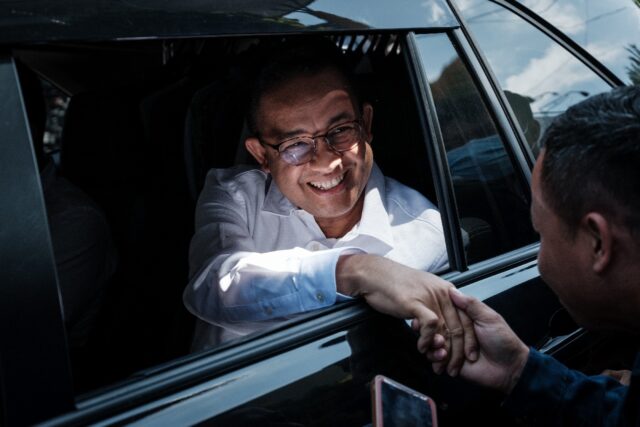 Presidential candidate Anies Baswedan shakes hands with a supporter as he arrives for a ca