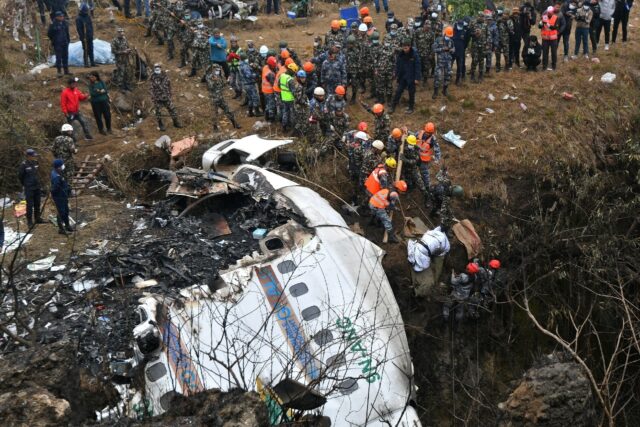 Rescuers pull the body of a victim who died in a Yeti Airlines plane crash in Nepal in Jan