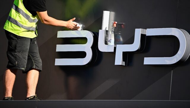 A worker cleans the company logo of Chinese carmaker BYD at their booth before the officia