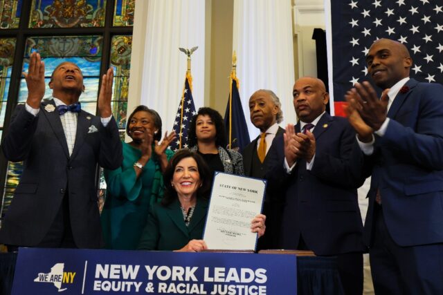 New York Governor Kathy Hochul holds up signed legislation creating a commission for the s