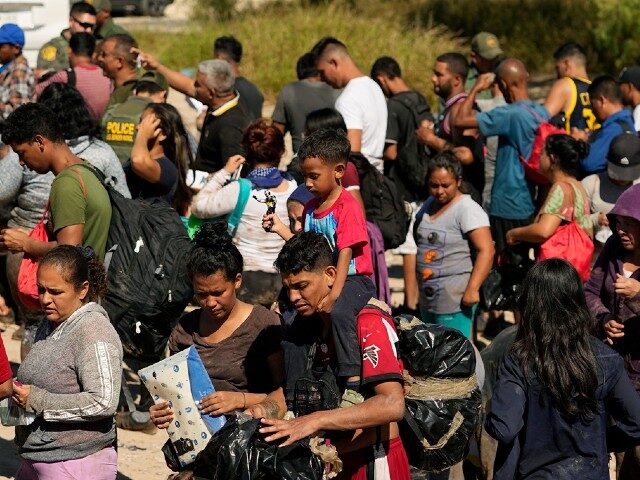 Migrants wait to be processed by the U.S. Customs and Border Patrol after they crossed the