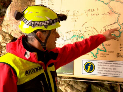 In this photo taken from video, a rescuer inspects the map of Krizna Jama cave near Grahov