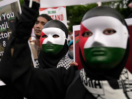 Protesters wearing masks with the colors of Palestinian flag hold posters during a rally i