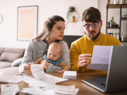 A young couple with a baby is worried about family budget and high taxes and bills.