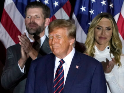 Republican presidential hopeful and former US President Donald Trump looks on, flanked by