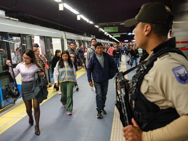 Police officers stand guard as commuters walk by at a subway station on January 10, 2024,